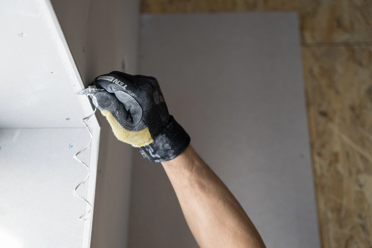 Professioneller Trockenbau: Ein Handwerker entgratet gerade die äußere Gipskartonplatte einer neuen Trockenbau-Fensternische.