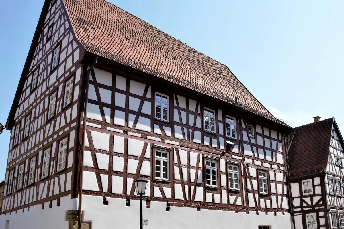 Denkmalpflege und Fassadenanstrich: Ein historisches Fachwerkhaus mit leuchtend weißen Gefachen und gepflegten, braunen Holzbalken.