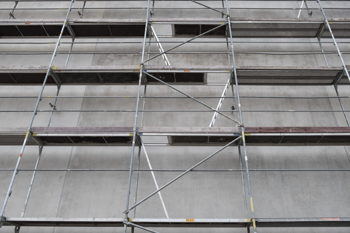 Fachgerechter Gerüstbau: Ein stabiles, mehrstöckiges Arbeitsgerüst aus Metall, das für Fassadenarbeiten sicher an einer Gebäudewand montiert ist.